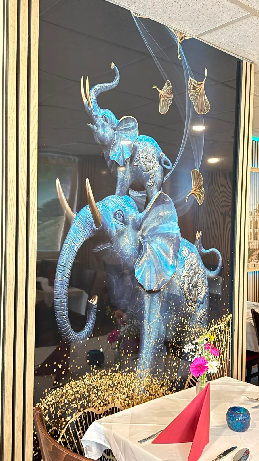 Nahaufnahme des Elefanten-Wandbilds: zwei blaue Elefanten, goldene Ginkgoblätter und gestreutes Blattgold.